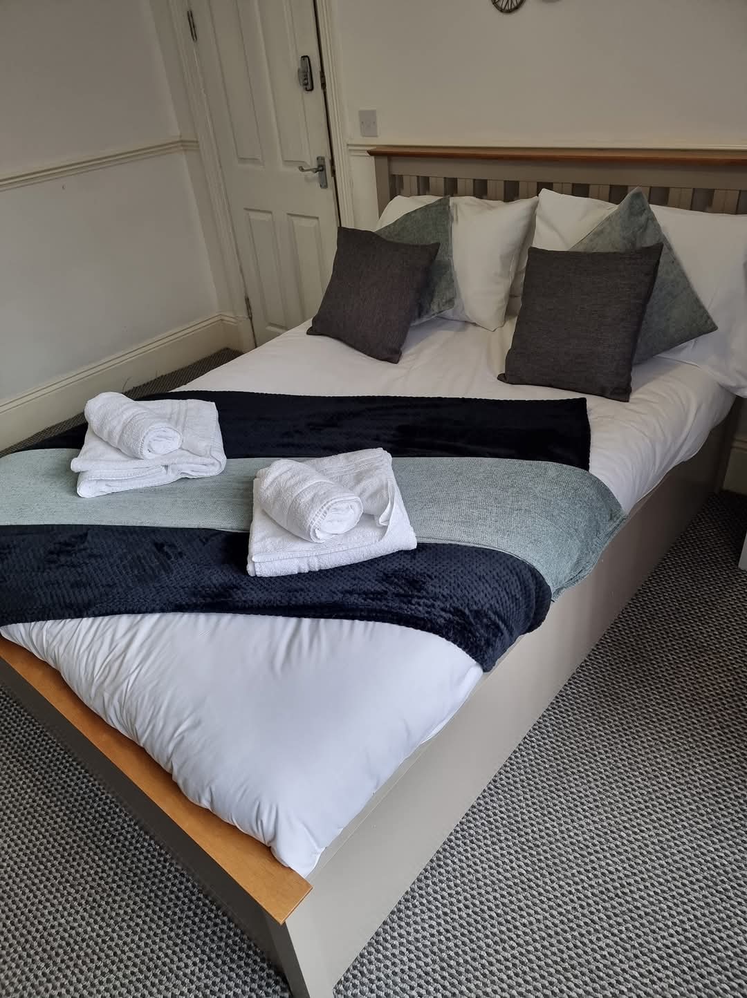 A freshly made bed with rolled towels, ready for the next guest